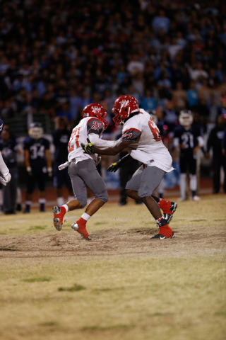 Arbor View High School’s Charles Louch (21) runs into lineman Quemaree Harris (67) in ...