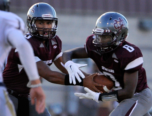 Cimarron-Memorial quarterback Derek Morefield, left, hands the ball off to Maurice Bennett o ...