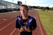 Ian Mack stands with his running spikes over his shoulder trackside at Green Valley High Sch ...