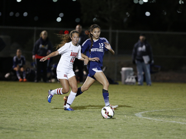Arbor View’s Hayley Vicente (12) and Shadow Ridge’s Casey Childers (12) close in ...