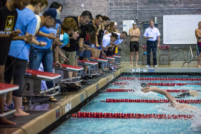 Time keepers lean in to see which swimmer touches the wall first during the Sunrise Region h ...