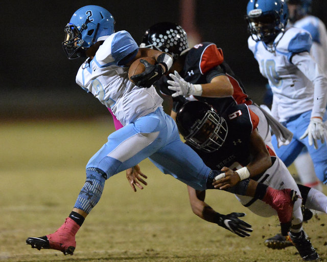 Canyon Springs junior Diamante Burton (2) tries to break a tackle from Las Vegas senior T.J. ...