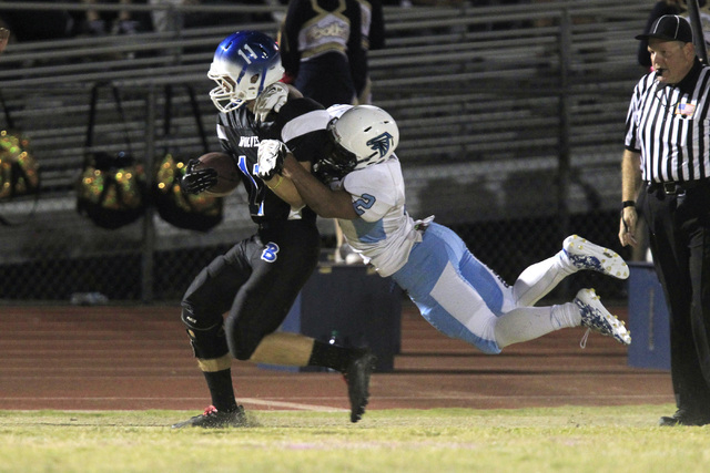 Basic wide receiver Chris Flum is brought down by Foothill defensive back Bobby Merritt duri ...