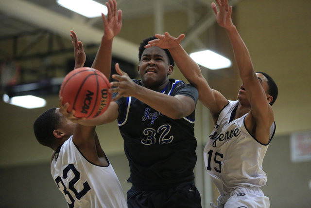 Desert Pines senior Derrick Coleman (32) tries to shoot the ball between two defenders durin ...