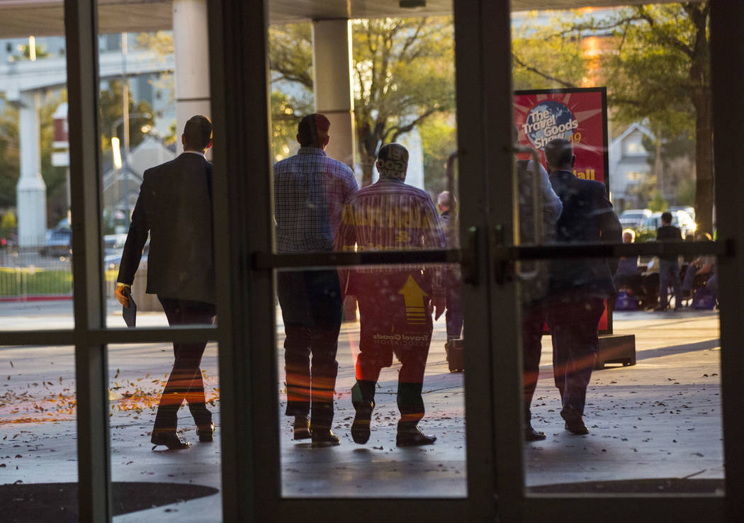 Plainclothes police officers walk out of the Las Vegas Convention Center after executing a sear ...