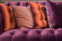 The sheen of satin pillows gives this violet velvet sofa a vintage style. (Getty Images)