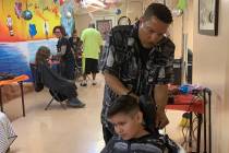 Thomas Rose, a volunteer at the Derfelt Back-to-School Haircuts & Eye Exams event, finishes a h ...