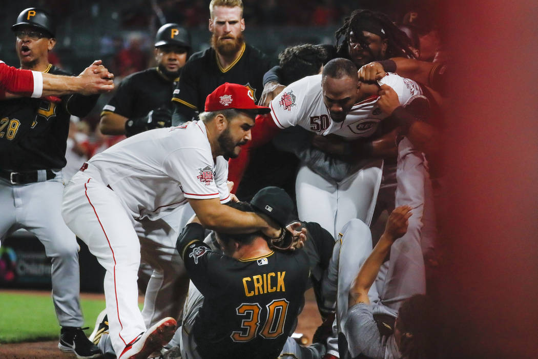 Pittsburgh Pirates' Kyle Crick (30) falls between Cincinnati Reds' Eugenio Suarez, left, and Am ...