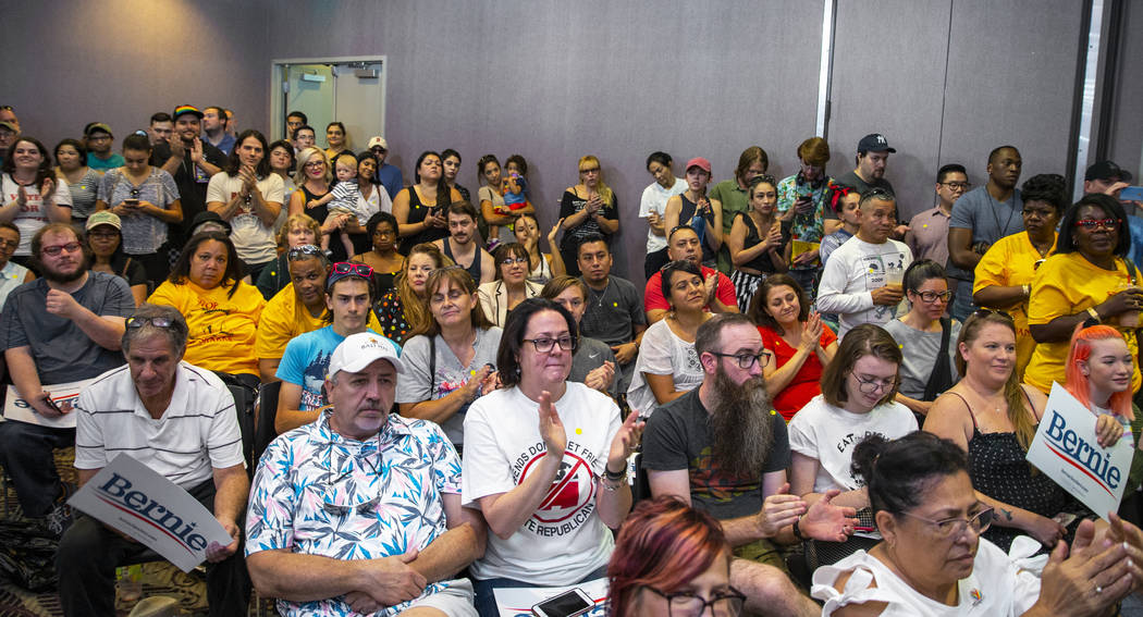 Audience members listen to Democratic presidential candidate Sen. Bernie Sanders, I-Vt., (out o ...