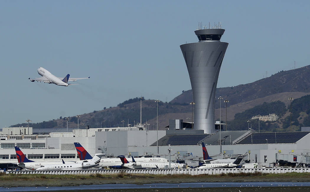 FILE - In this Oct. 24, 2107 file photo, the air traffic control tower is in sight as a plane t ...