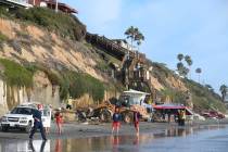 Search and rescue personnel work at the site of a cliff collapse at a popular beach Friday, Aug ...