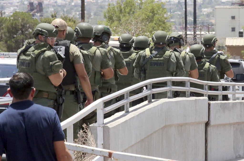 Law enforcement officers make their way along a walkway to the scene of a shooting at a shoppin ...