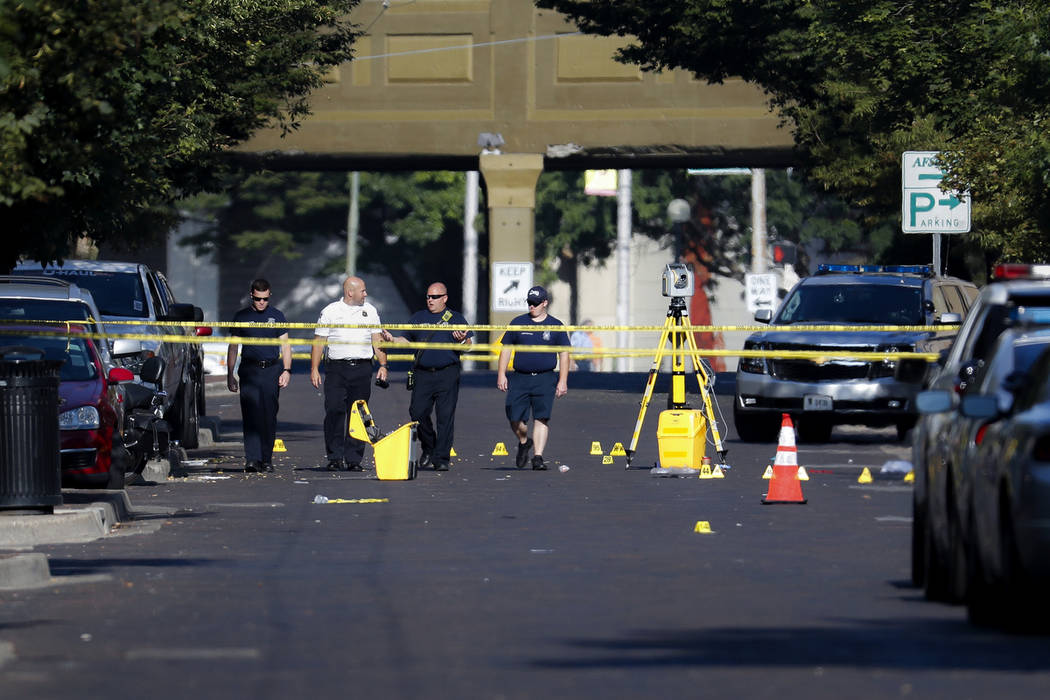 Authorities walk among evidence markers at the scene of a mass shooting, Sunday, Aug. 4, 2019, ...