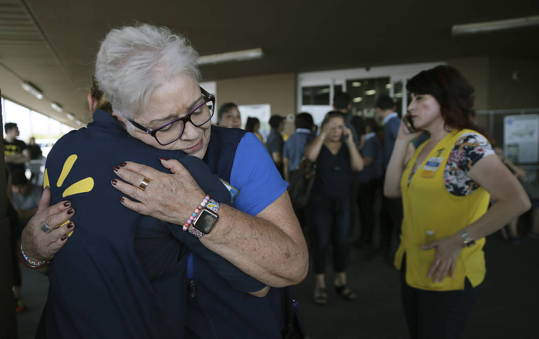 Walmart employees comfort one another after an active shooter opened fire at the store in El Pa ...