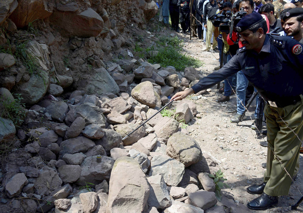 A police officer points to a munition fired by Indian forces that landed in Nosehri village on ...