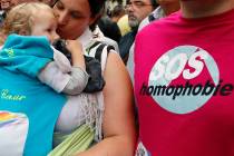 FILE - In this Saturday, June 28, 2014 file photo a woman kisses a baby next to a man wearing a ...
