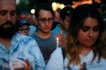 Mourners bow their heads in prayer as they gather for a vigil at the scene of a mass shooting, ...