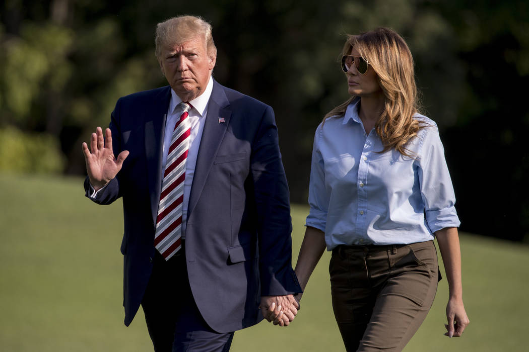 President Donald Trump waves to members of the media as he and first lady Melania Trump walk ac ...