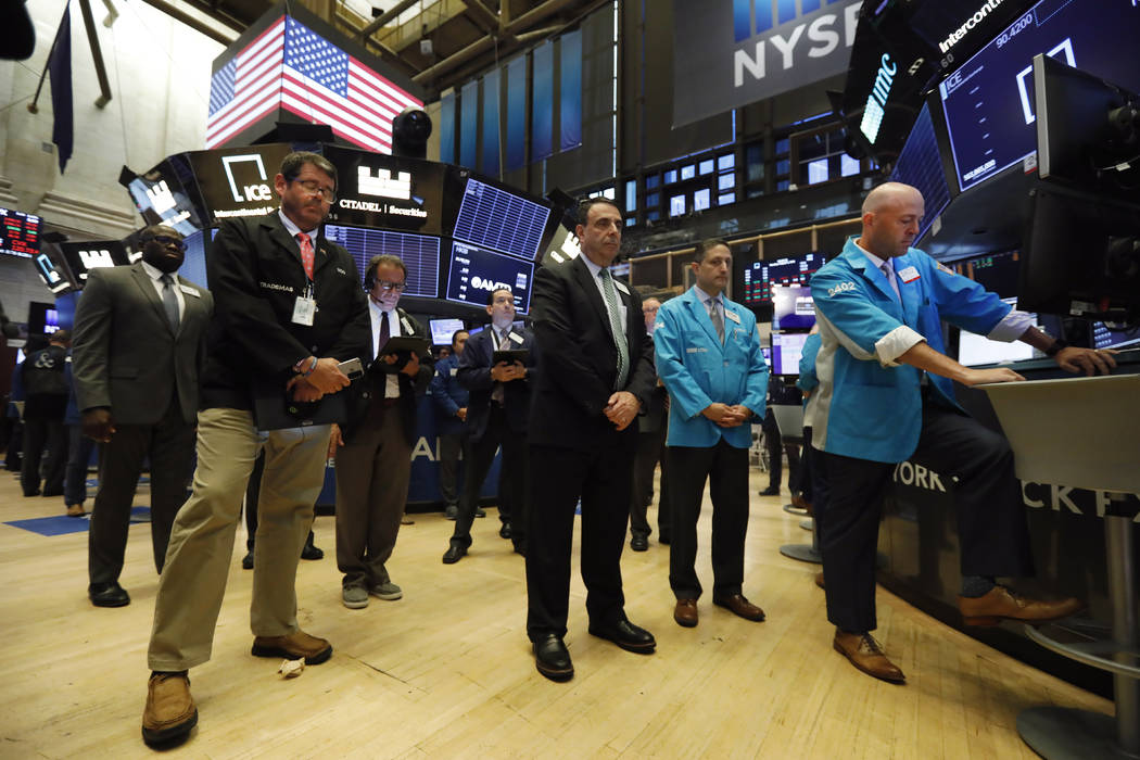 Traders pause for a moment of silence on the floor of the New York Stock Exchange, for the vict ...