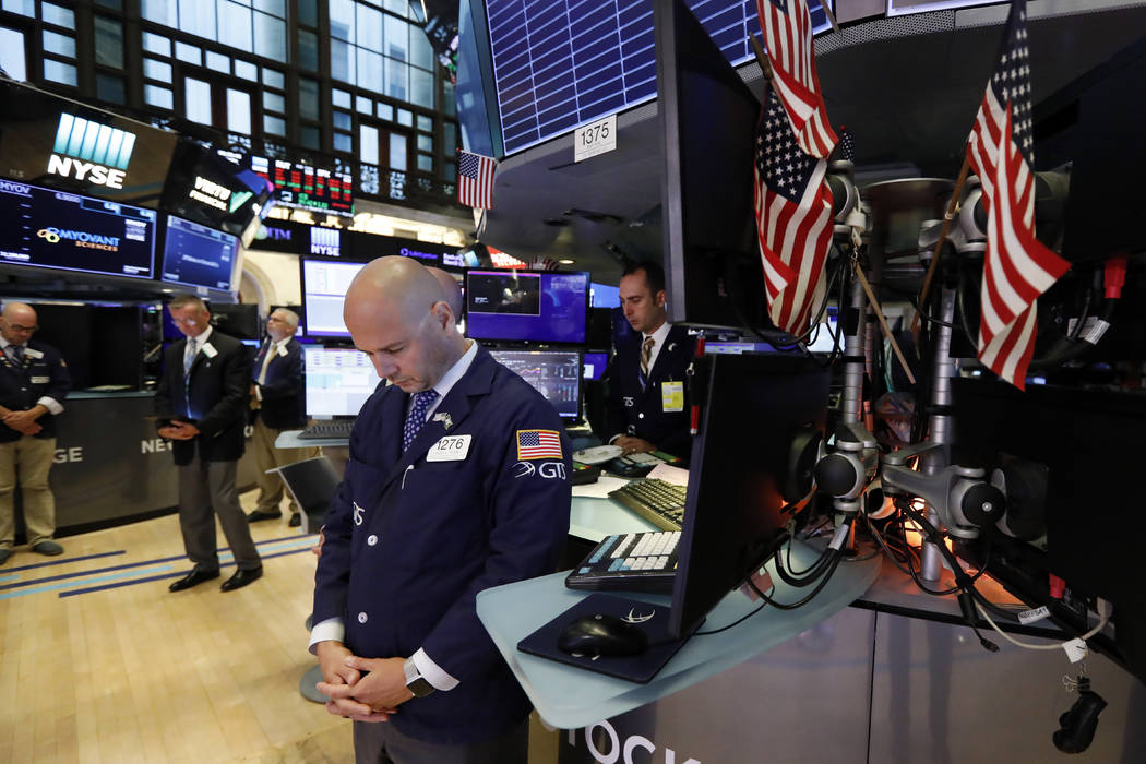 Traders pause for a moment of silence on the floor of the New York Stock Exchange, for the vict ...