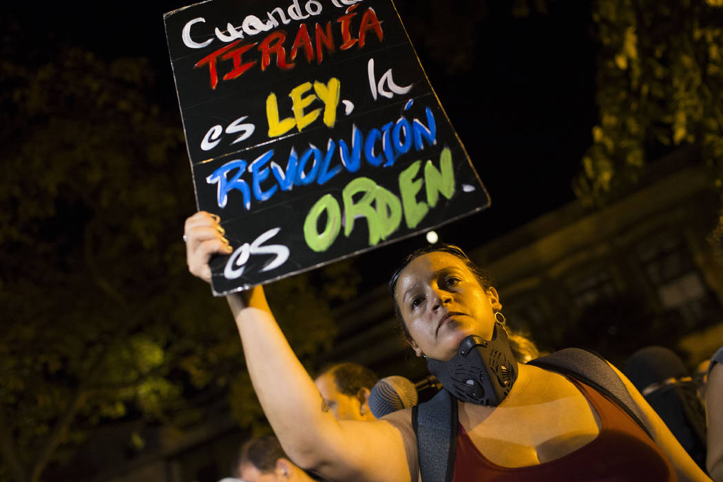 A woman holds a sign with message that reads in Spanish: "When tyranny is the law, a revol ...