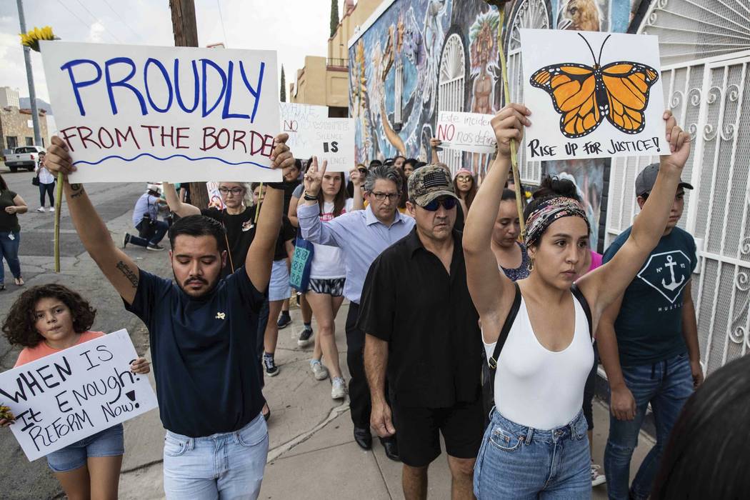 People march in silence Sunday, Aug. 4, 2019, in El Paso, Texas, holding sunflowers and signs t ...
