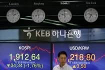 A currency trader walks by the screens showing the Korea Composite Stock Price Index (KOSPI), l ...