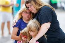 Mourners embrace after bringing flowers to a makeshift memorial Tuesday, Aug. 6, 2019, for the ...