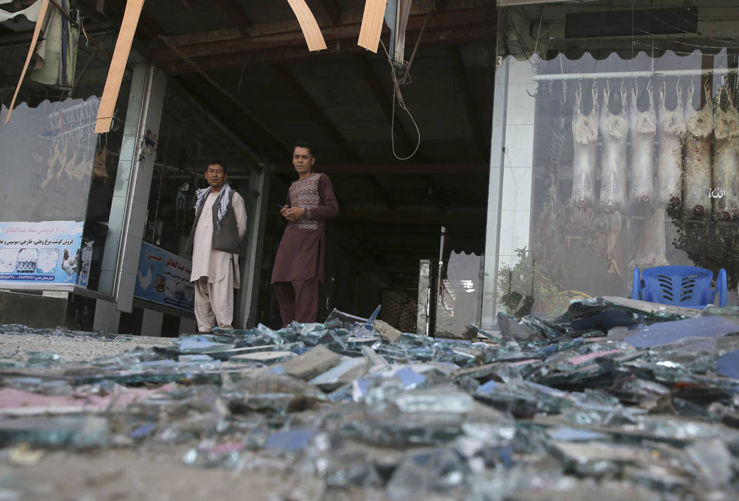 Afghans stand near a damaged shop after an explosion in Kabul, Afghanistan, Wednesday, Aug. 7, ...