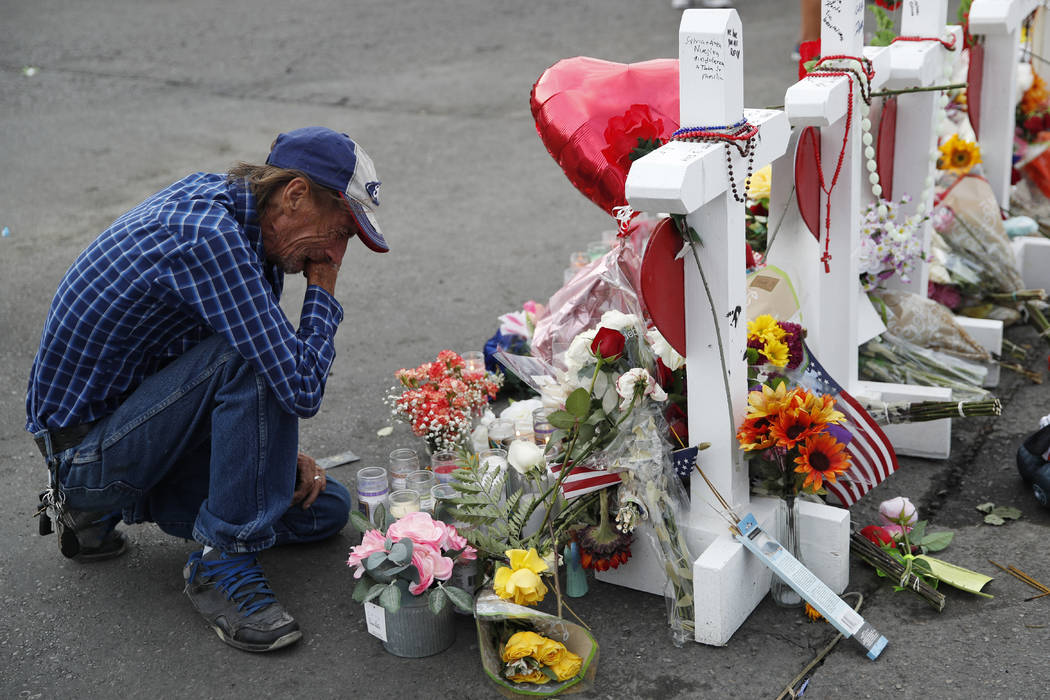 A man cries beside a cross at a makeshift memorial near the scene of a mass shooting at a shopp ...