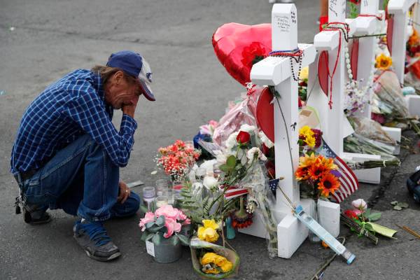 A man cries beside a cross at a makeshift memorial near the scene of a mass shooting at a shopp ...