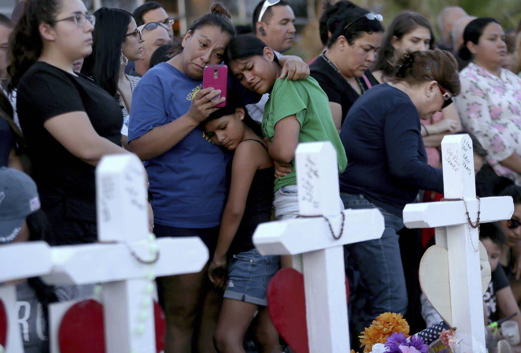 A mother clings to her daughters as they visit a memorial for the victims of Saturday's mass sh ...