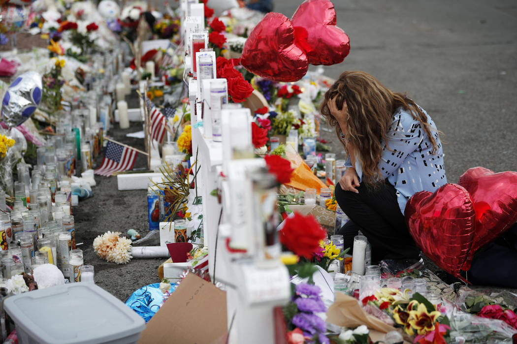 Gloria Garces kneels in front of crosses at a makeshift memorial near the scene of a mass shoot ...