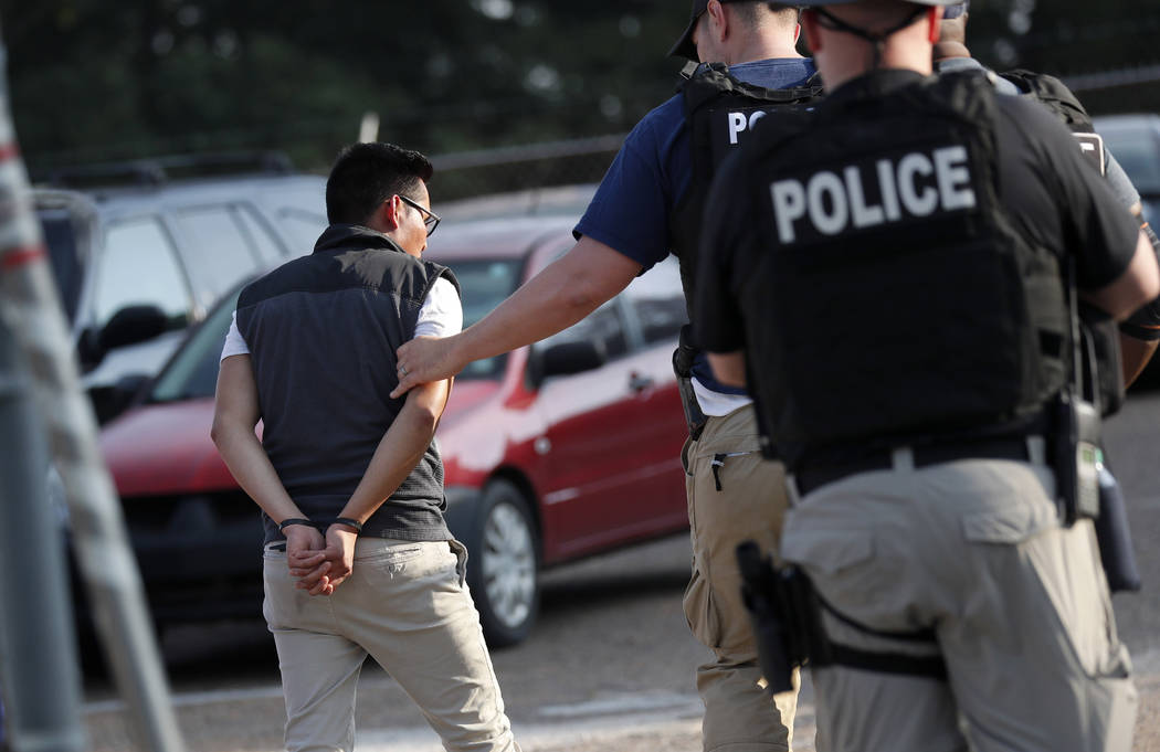 A man is taken into custody at a Koch Foods Inc. plant in Morton, Miss., on Wednesday, Aug. 7, ...