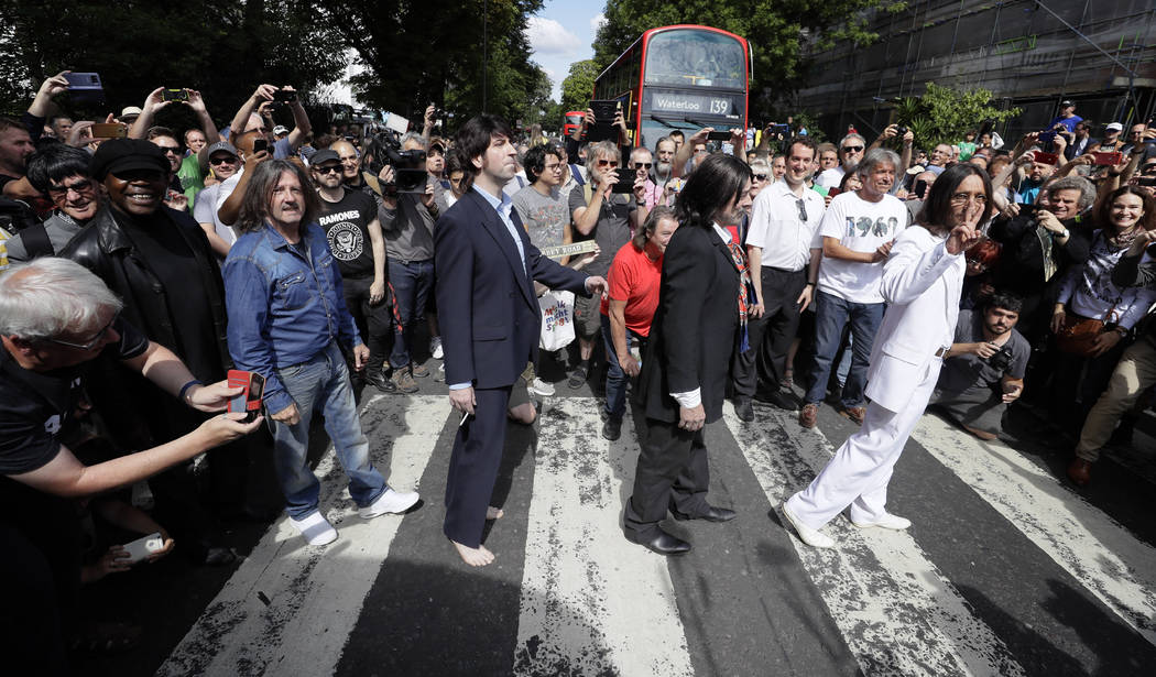 Fans dressed as lookalikes walk across the Abbey Road zebra crossing on the 50th anniversary of ...