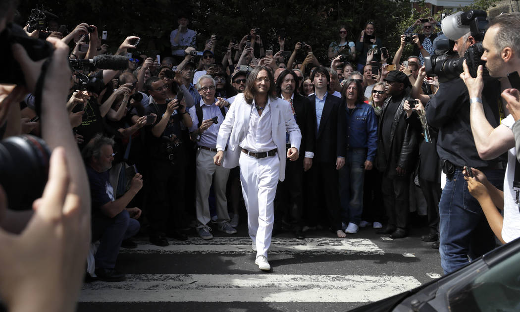 Thousands of fans gather to walk across the Abbey Road zebra crossing, on the 50th anniversary ...