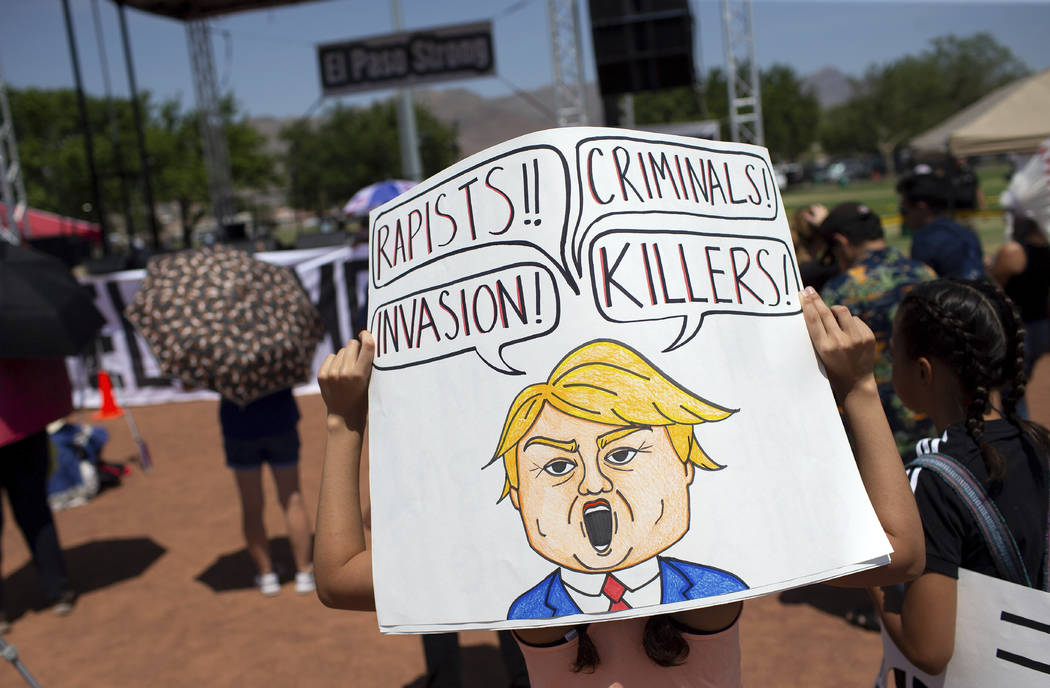 A demonstrator holds a sign to protest the visit of President Donald Trump to the border city a ...