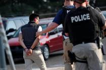 A man is taken into custody at a Koch Foods Inc. plant in Morton, Miss., on Wednesday, Aug. 7, ...