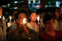 People attend a candlelight vigil for victims of a mass shooting at a shopping complex over the ...