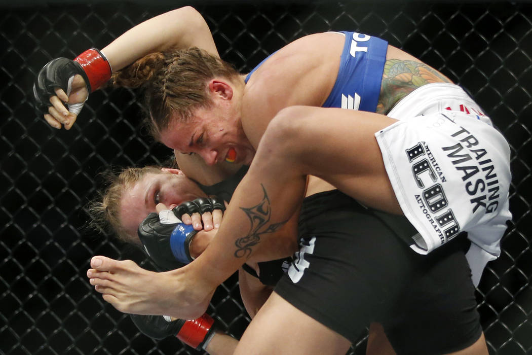 Liz Carmouche, top, grapples with Ronda Rousey during their UFC 157 women's bantamweight champi ...