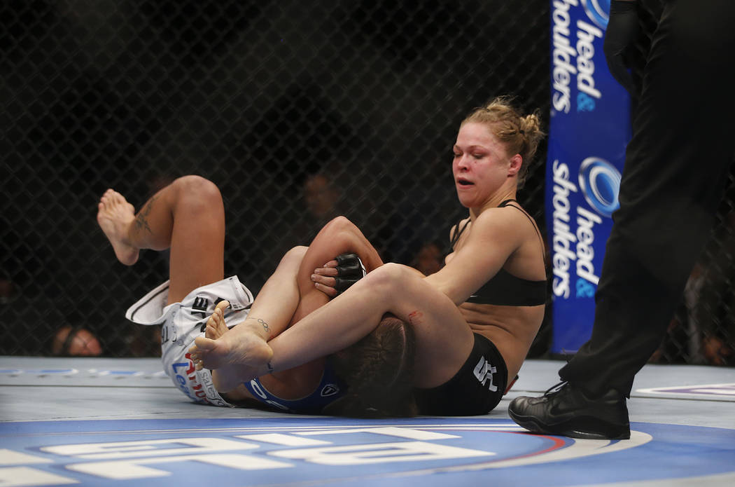 Ronda Rousey, right, tries to pull an arm bar on Liz Carmouche during their UFC 157 women's ban ...