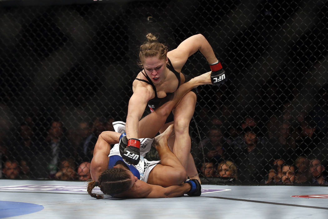 Ronda Rousey, top, punches Liz Carmouche during their UFC 157 women's bantamweight championship ...