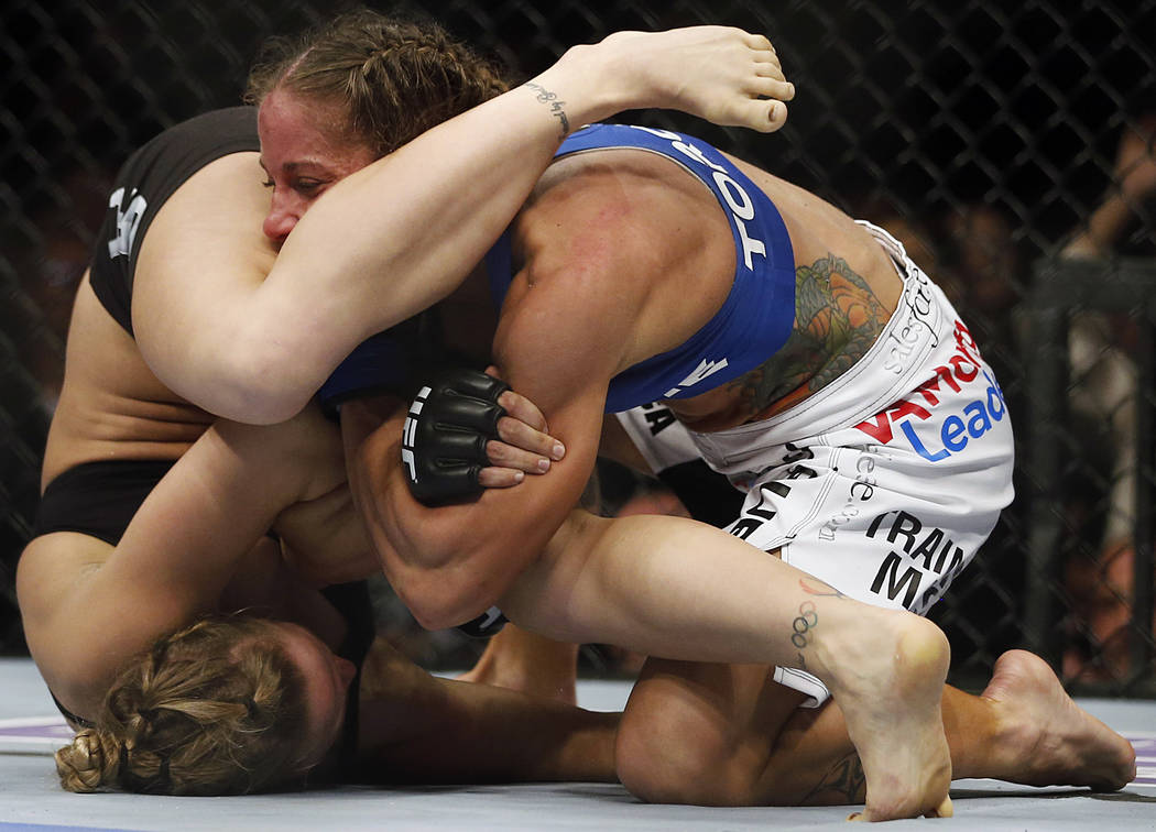 Ronda Rousey, left, tries to pull an armbar on Liz Carmouche during their UFC 157 women's banta ...