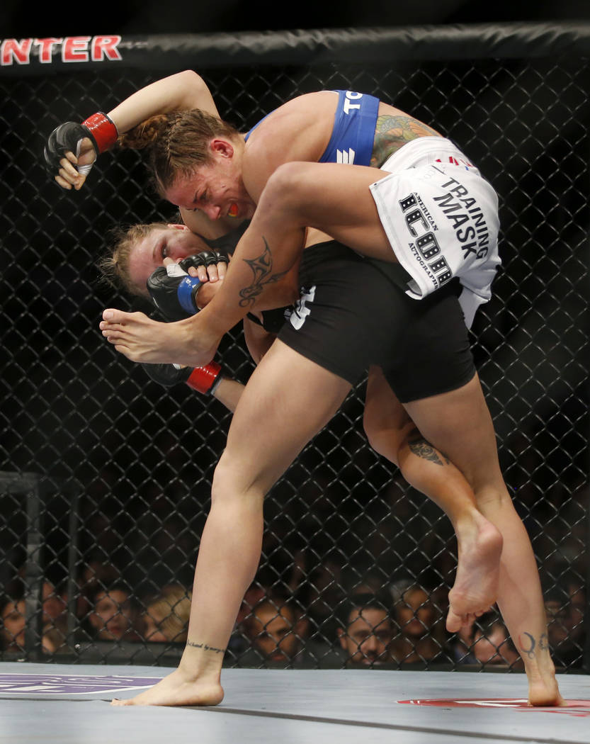 Liz Carmouche, top, tries to choke Ronda Rousey during their UFC 157 women's bantamweight champ ...