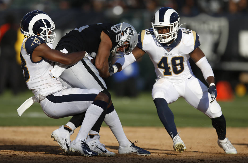 Oakland Raiders' Derek Carrier, center, is tackled by Los Angeles Rams' Mike Thomas, left, and ...