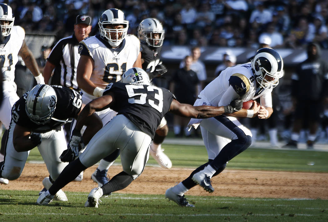 Los Angeles Rams quarterback Brandon Allen, right, evades a tackle by Oakland Raiders' Jason Ca ...