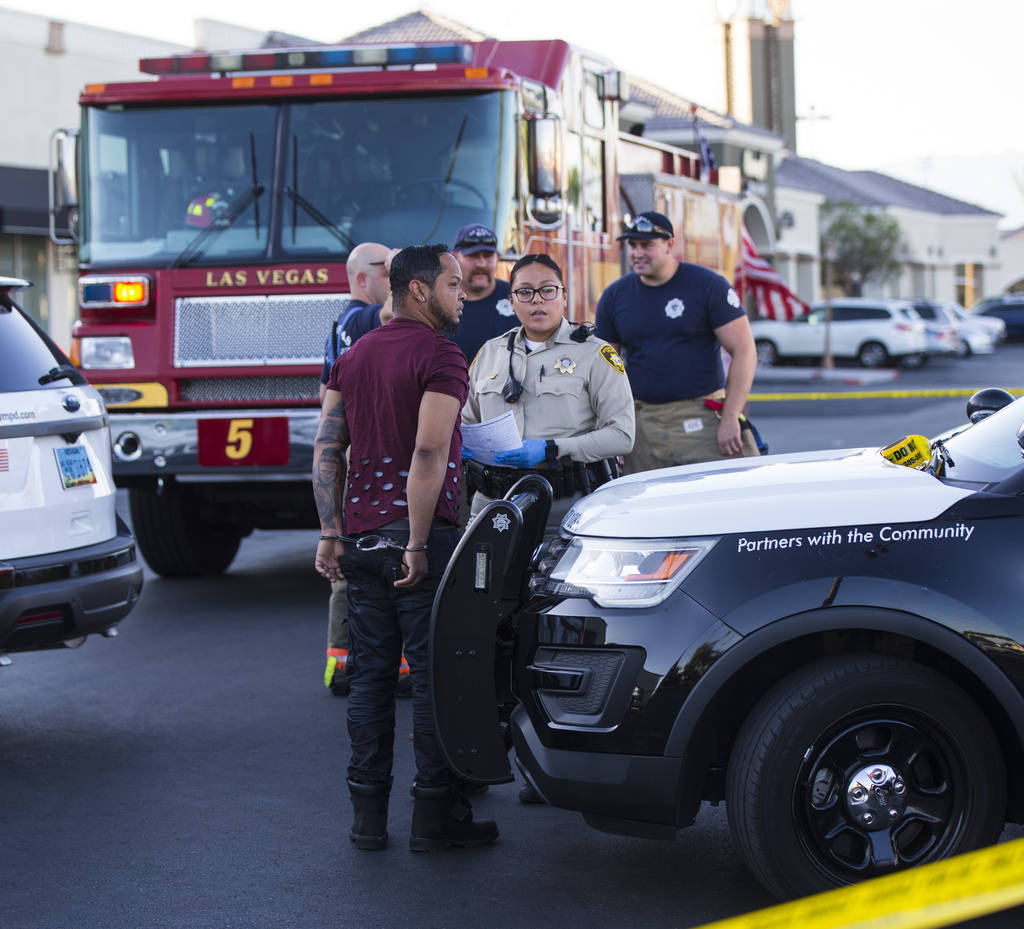 A man is detained by Las Vegas police as they investigate the scene where a driver in a car cra ...
