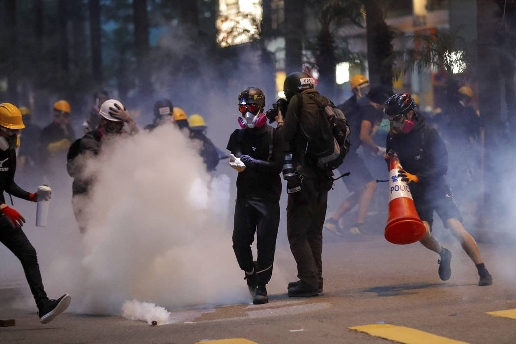 Protesters use traffic cones to cover the tear gas canisters fired by riot policemen during the ...