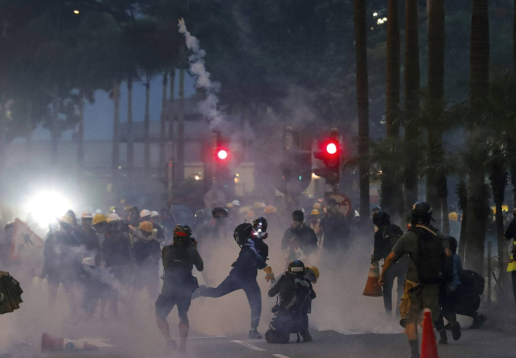 A protester throws a tear gas canister fired by riot policemen during the anti-extradition bill ...