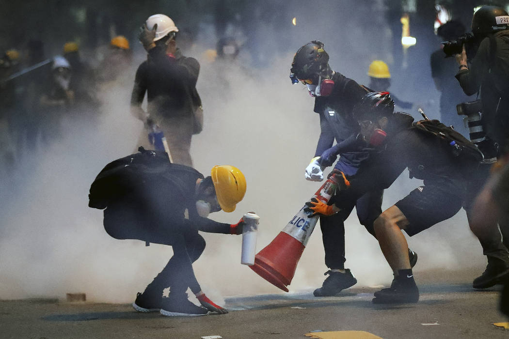 Protesters use traffic cones to cover the tear gas canisters fired by riot policemen during the ...